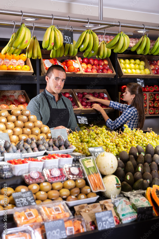 .Young salesman selling fresh fruits and vegetables at a market.