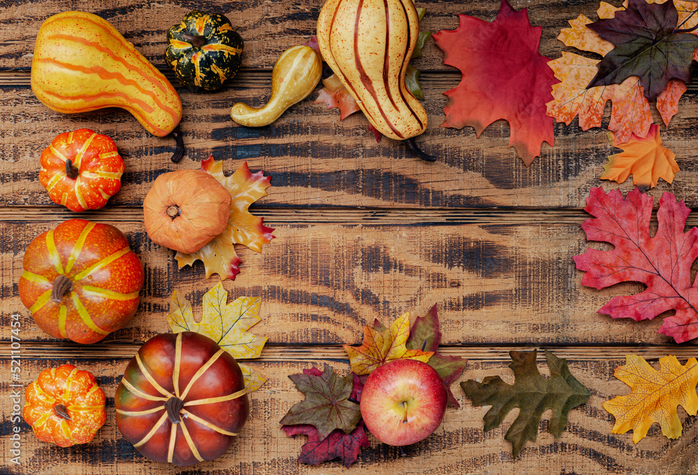 Autumn colorful pumpkins, apples and fallen leaves on a textured wood background. View from above. Autumn colorful pumpkins, apples and fallen leaves on a textured wood background. View from above.