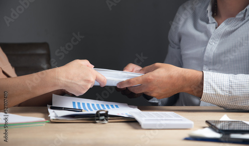 man and woman handing documents to each other