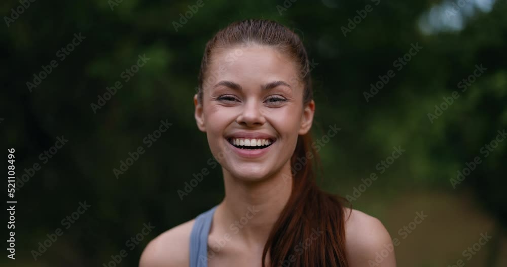Close-up portrait of a laughing woman in a sports top in the park looking into the camera, feminine energy and happiness with a beautiful smile Close-up portrait of a laughing woman in a sports top in the park looking into the camera, feminine energy and happiness with a beautiful smile