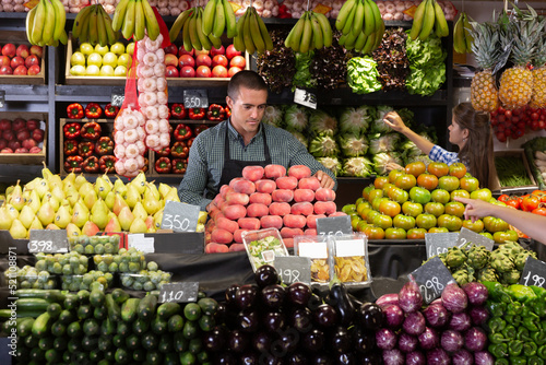 Posing male and working woman in fruit and vegetable shop photo