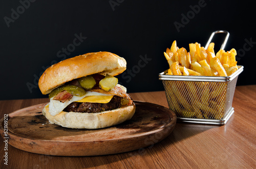 the photograph shows a delicious hamburger accompanied by french fries