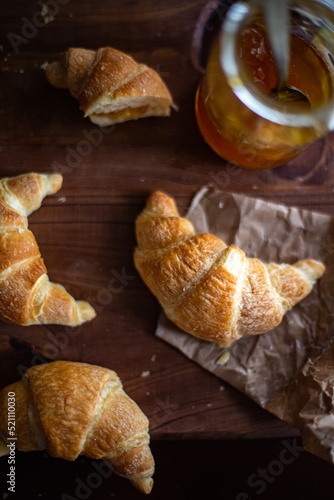 Small fresh croissants and a jar of fruit jen on a wooden table. Traditional Argentine medialoons. flat lay composition. photo