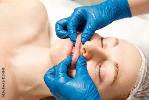 A rejuvenating treatment for the skin of the face. Cosmetologist makes a buccal massage of the patient's facial muscles.