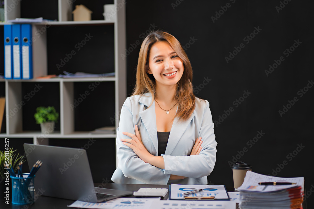 Happy young asian businesswoman sitting on her workplace in the office. Young woman working at laptop in the office Happy young asian businesswoman sitting on her workplace in the office. Young woman working at laptop in the office