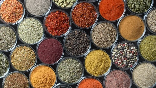 Assortment of aromatic spices, seeds and dry herbs for cooking food on background rotating in smal glass bowls rotating, close up, top view