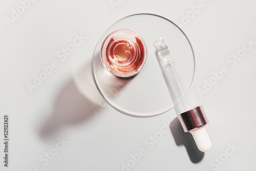 Oil or Serum bottle and pipette in petri dish on grey background. Pink cosmetic product