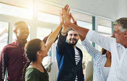 Corporate businesspeople celebrate success in an office. Passionate people feeling motivated, confident and cheerful. Excited, smiling and diverse professional group happy with their big win. photo