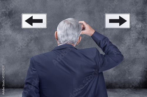 фотографія A rear view of thinking, confused and deciding businessman struggling and trying to decide which way to go