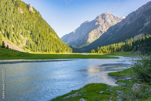 Idyllic summer landscape with hiking trail in the mountains with river with reflection and forest.