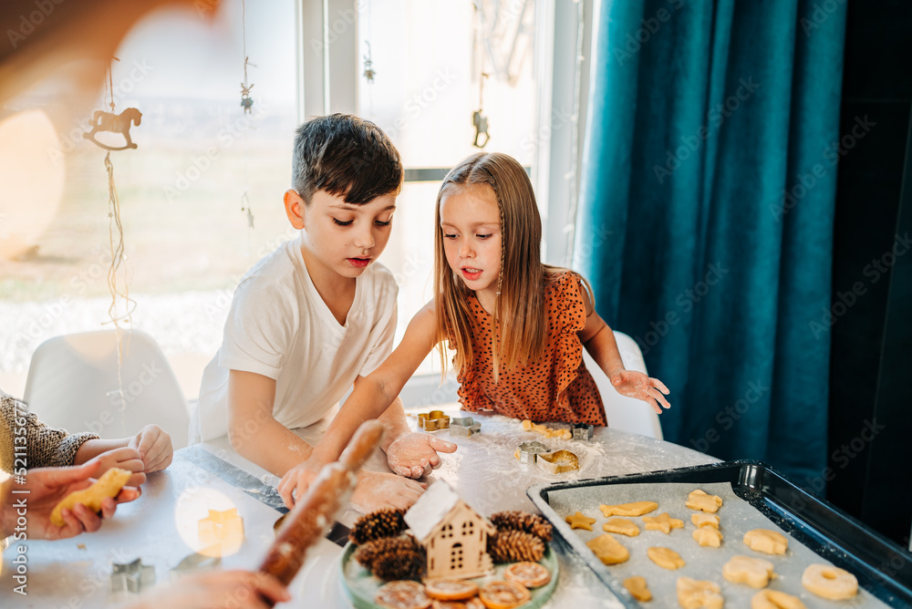 Happy kids cooking cookies bakery together and having fun with flour indoors at cozy home on the kitchen table. Siblings in big loving family Happy kids cooking cookies bakery together and having fun with flour indoors at cozy home on the kitchen table. Siblings in big loving family