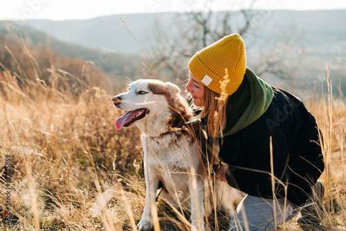 Young woman and her husky dog trek down a forest trail offering a scenic view of the trees changing colors. Fit girl takes her miniature pinscher for a walk in woods