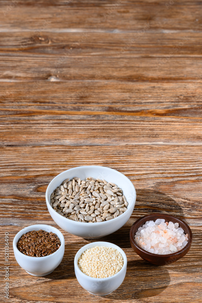 Flax and sunflower seeds, salt and sesame on a dark wooden table Flax and sunflower seeds, salt and sesame on a dark wooden table