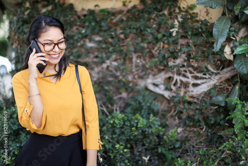 Young latin american woman using phone smiling with leaves background at Costa Rica