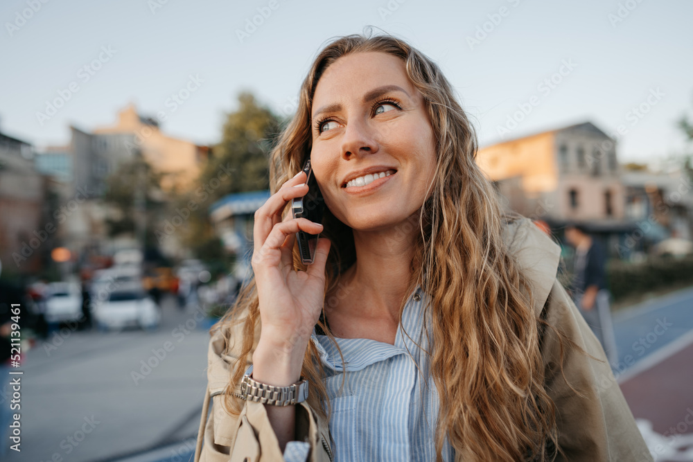 Young casual woman talking on the smartphone at the city