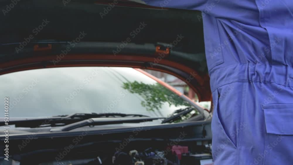 The mechanic is checking the condition of the car's engine. before delivering the car to the customer using a tablet and paper check list. The mechanic is checking the condition of the car's engine. before delivering the car to the customer using a tablet and paper check list.
