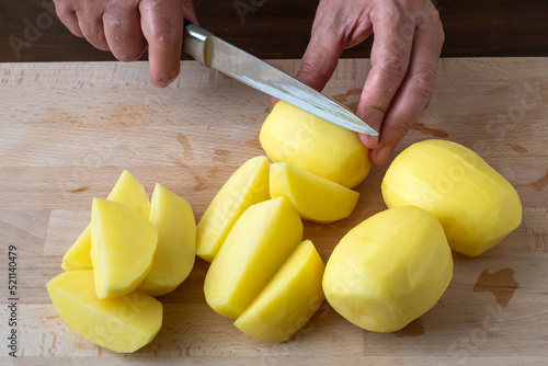 Hands with knife cutting potatoes, preparing potatoes for cooking.