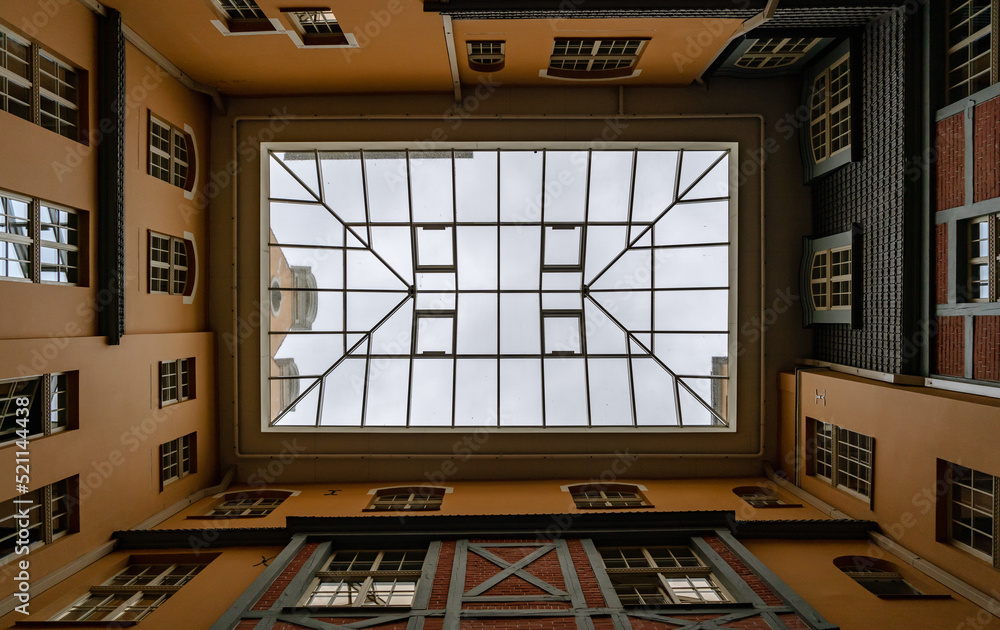 Below view of glass roof from courtyard to old-style brick and orange houses