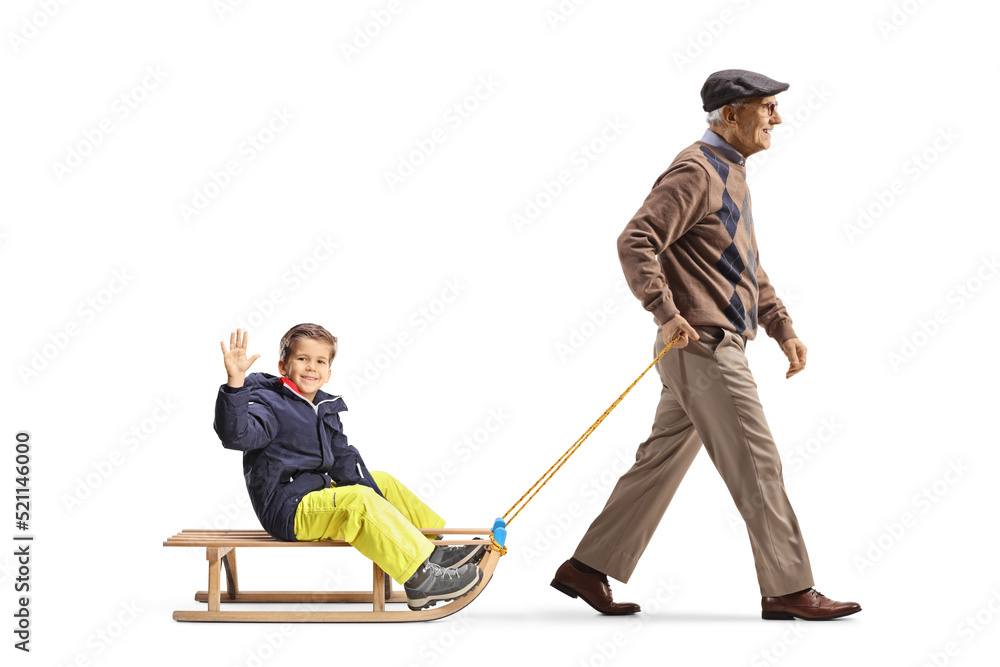 Full length profile shot of a grandfather walking and pulling a boy on a sled Full length profile shot of a grandfather walking and pulling a boy on a sled