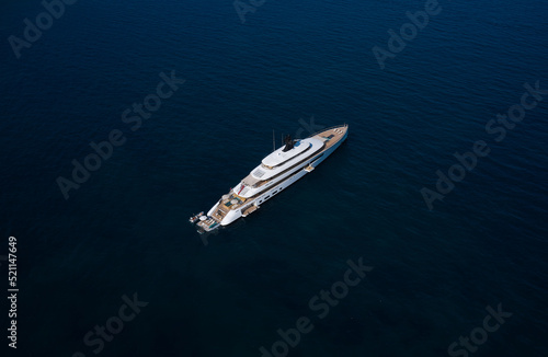 White big yacht at anchor aerial view. Mega yacht on dark water aerial view. Modern big white yacht on the water top view. © Berg
