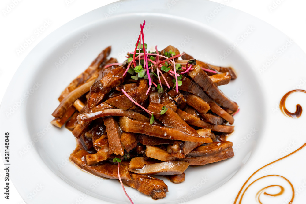 Fried pieces of pork in sauce decorated with microgreens. Marinated pig ears Fried pieces of pork in sauce decorated with microgreens. Marinated pig ears