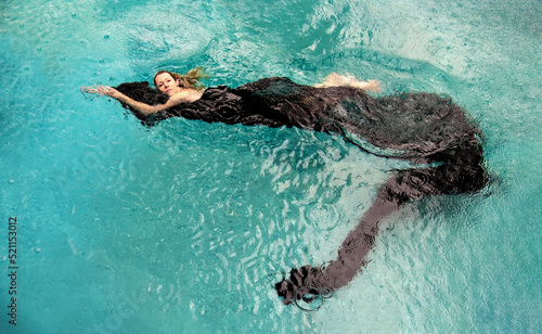 top view to a beautiful sexy young woman floating like a mermaid in black cloth dress wrapped in green water of the swimming pool, elegant erotic dream photo