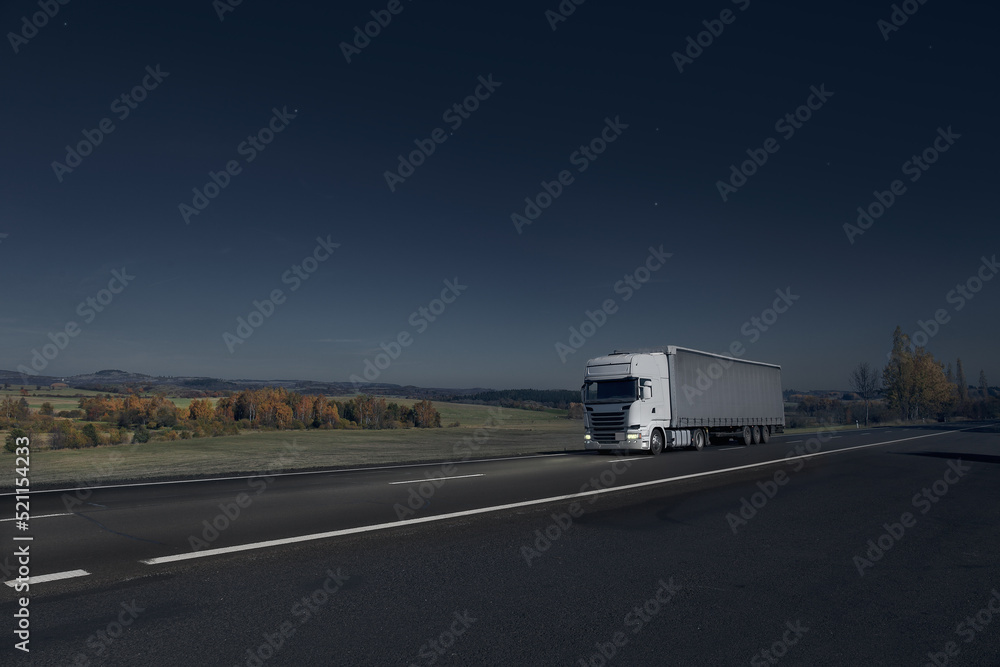 Truck driving through the night landscape at moonlight