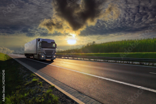 Landscape with a moving truck on the highway at sunset.