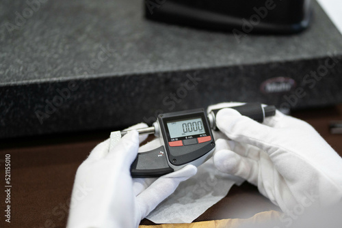Industrial worker measure detail with digital caliper micrometer at factory workshop
