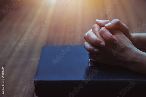 Canvastavla Prayer hands on the holy bible on wooden table with window light background