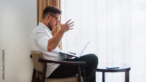 Obraz na płótnie Male businessman in a white shirt working at a laptop in the office, during a conversation, online meeting, remote work. w salonie