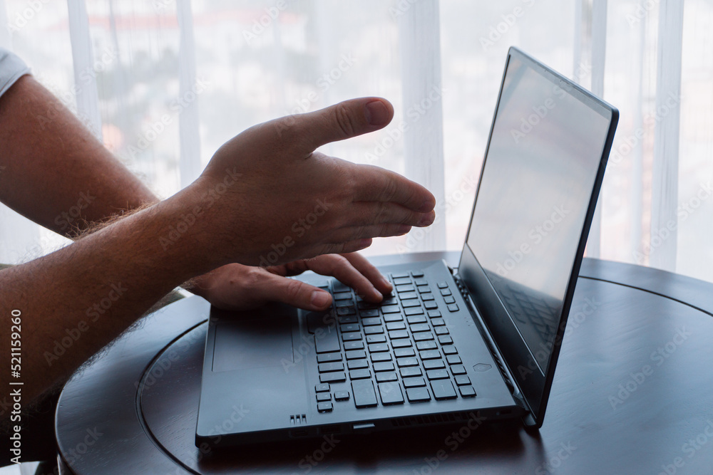 Man working on a laptop, hands close-up, remote work, photo on a light background, project management.