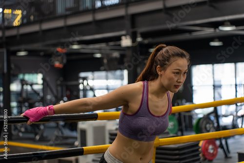 Asian sportswoman pulling the rope on the boxing ring in the gym. combat sports and healthy concept. Thai boxing, Muay Thai. © suwanb