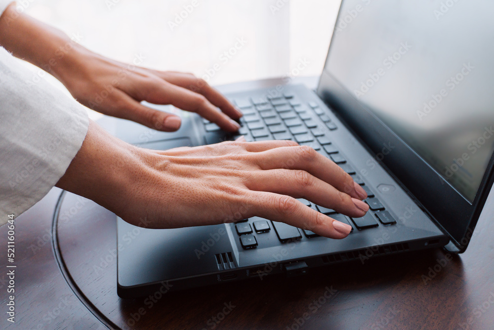 A woman working on a laptop, closeup of her hands and keyboard, the blank screen in the form of a clean template, businesswomen in the office on a light background.