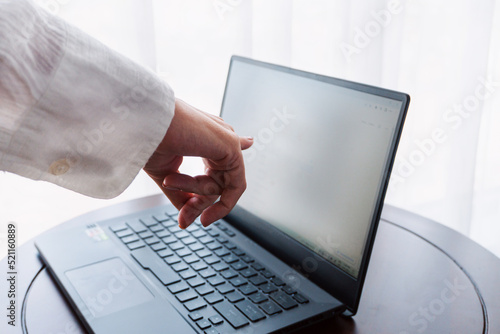 Obraz na płótnie A woman working on a laptop, closeup of her hands and keyboard, the blank screen in the form of a clean template, businesswomen in the office on a light background. w salonie