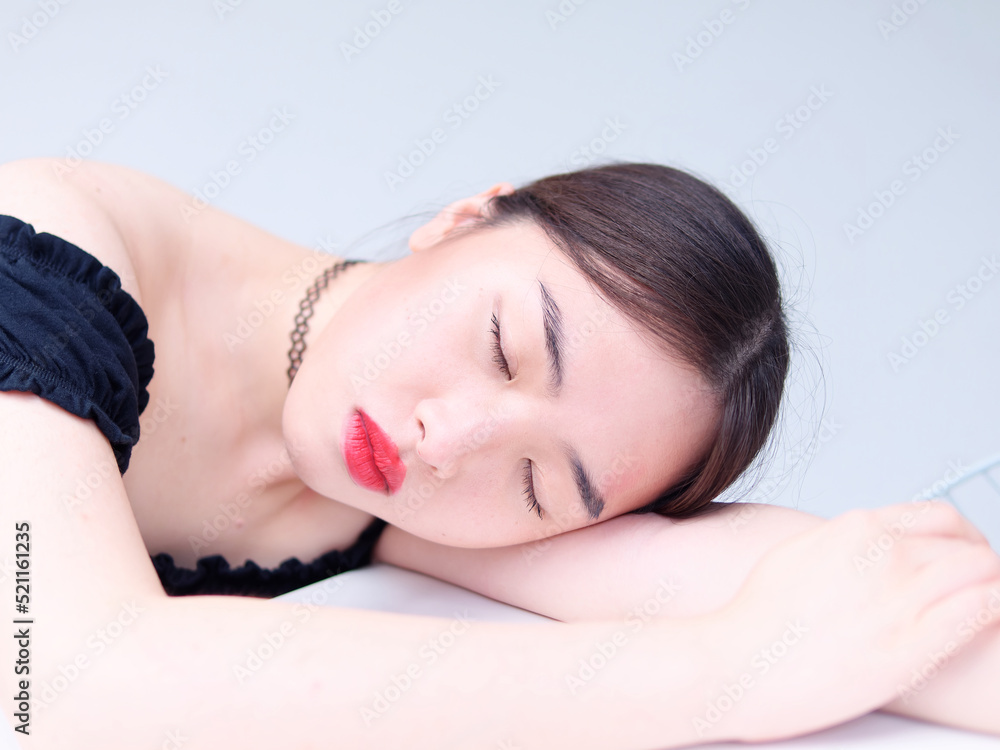 Portrait of beautiful Chinese young girl wearing black tube dress sitting and sleeping on table, indoor fashion portrait of glamour sexy stylish lady with black long hair. Portrait of beautiful Chinese young girl wearing black tube dress sitting and sleeping on table, indoor fashion portrait of glamour sexy stylish lady with black long hair.