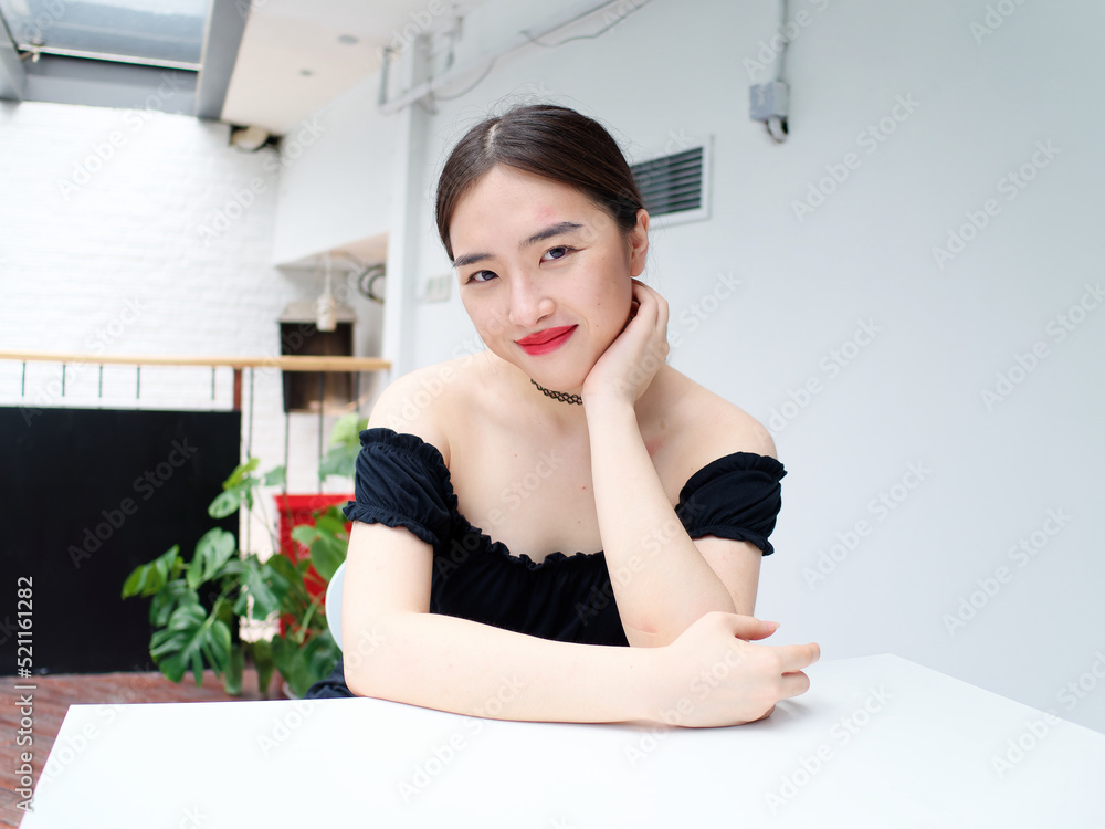 Portrait of beautiful Chinese young girl wearing black tube dress sitting and smiling at camera in shopping mall, indoor fashion portrait of glamour sexy stylish lady with black long hair. Portrait of beautiful Chinese young girl wearing black tube dress sitting and smiling at camera in shopping mall, indoor fashion portrait of glamour sexy stylish lady with black long hair.