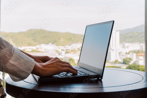 Obraz na płótnie A woman working on a laptop, closeup of her hands and keyboard, the blank screen in the form of a clean template, businesswomen in the office on a light background. w salonie