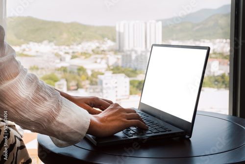 Obraz na płótnie A woman working on a laptop, closeup of her hands and keyboard, the blank screen in the form of a clean template, businesswomen in the office on a light background. w salonie