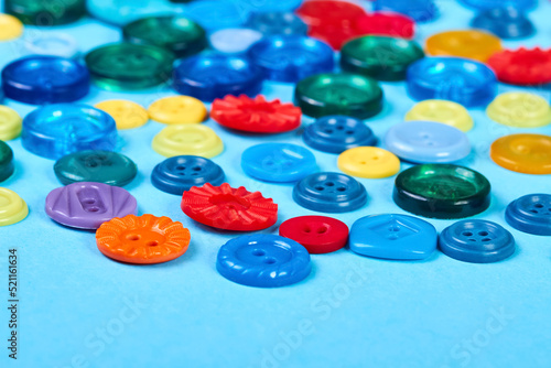Multicolored buttons for clothess on a blue background. Close-up, selective focus