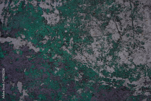 Old concrete wall mottled with traces of past paint layers of green and silver color. Grunge design background