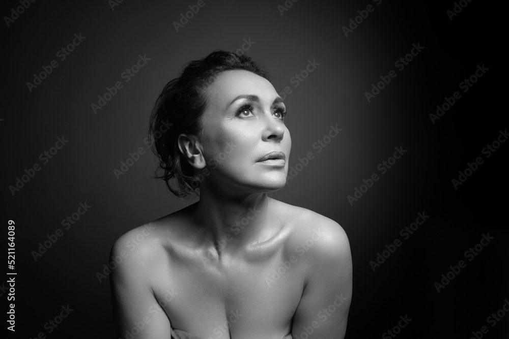 Portrait of a sensual fifty year old woman on grey studio background. Monochrome shot. Portrait of a sensual fifty year old woman on grey studio background. Monochrome shot.