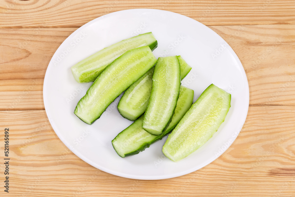 Halved small cucumbers on a dish on a rustic table Halved small cucumbers on a dish on a rustic table