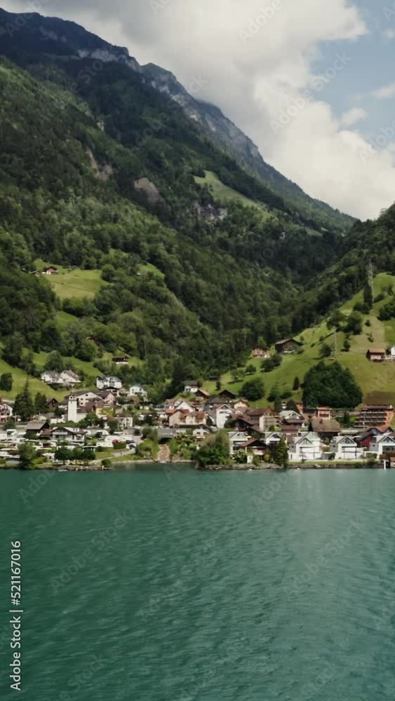 Modern village in a lowland between the Alpine mountains on the lakeshore Modern village in a lowland between the Alpine mountains on the lakeshore