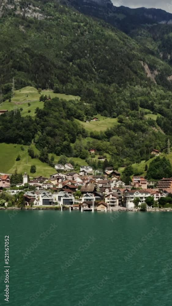 Modern village in a lowland between the Alpine mountains on the lakeshore Modern village in a lowland between the Alpine mountains on the lakeshore