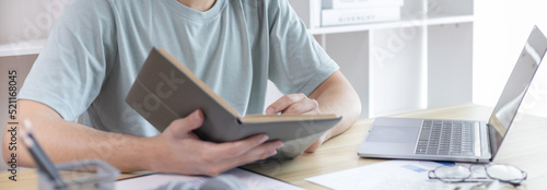 Asian man taking notes in notebook while studying online in laptop at home, Video chat, Online communication , Stay home, New normal, Distance learning., Social distancing, Learn online..