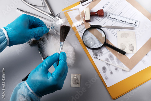 Forensic fingerprinting, forensic expert handles a glass goblet with a fingerprint brush photo
