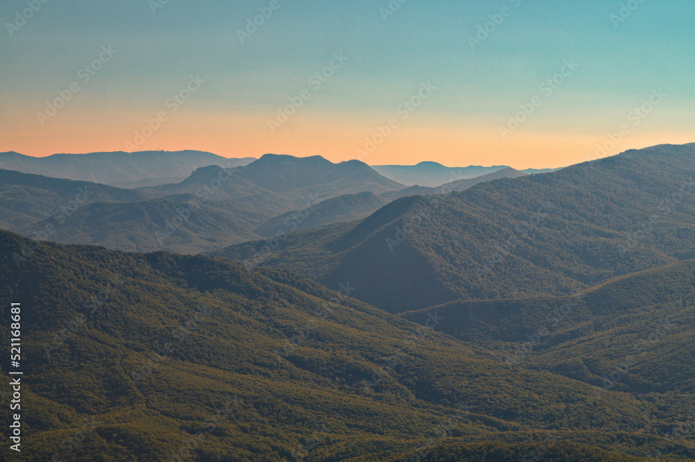 View of mountain wooded peaks at sunset
