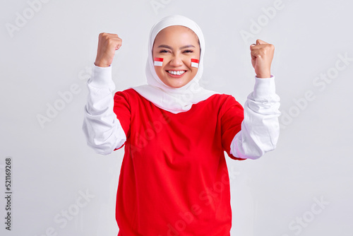 Excited young Asian muslim woman in red white t-shirt celebrating indonesian independence day on 17 august isolated on white background