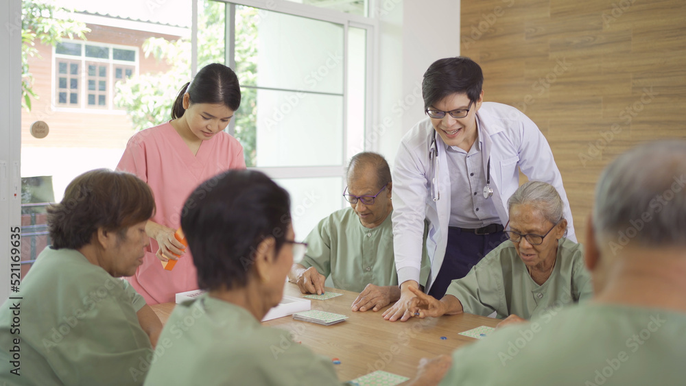 Portrait of happy group of old elderly Asian patient or pensioner people with a nurse and doctor playing games in nursing home. Senior lifestyle activity recreation. Retirement community. Health care Portrait of happy group of old elderly Asian patient or pensioner people with a nurse and doctor playing games in nursing home. Senior lifestyle activity recreation. Retirement community. Health care